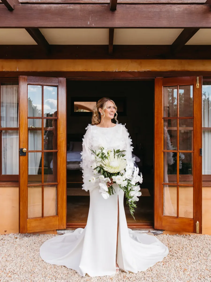 Bride in a feathered gown standing in a timber doorway