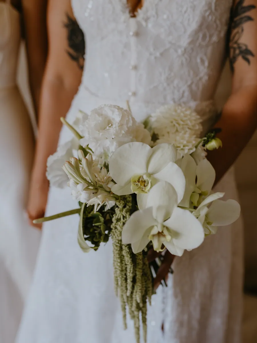 Orchid and amaranthus bouquet held against a lace gown