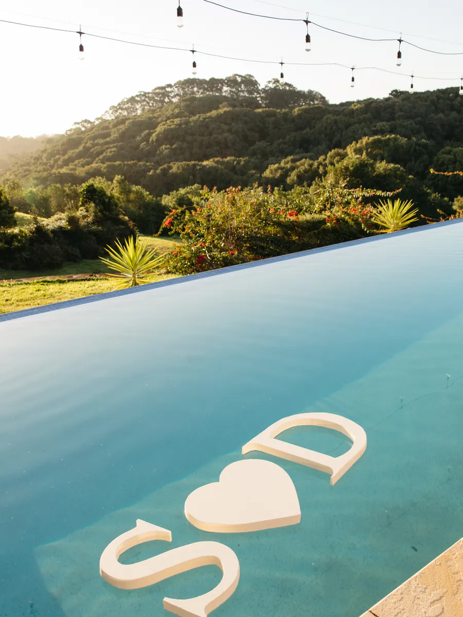 Couple&rsquo;s initials floating in an infinity pool above the hinterland