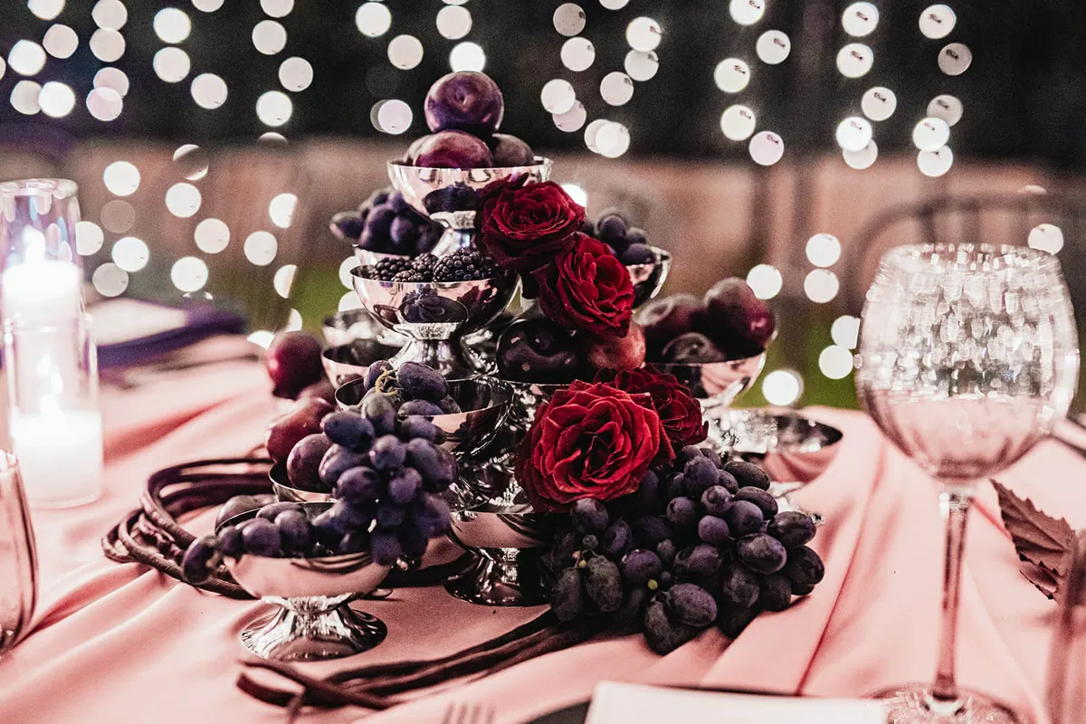 Grapes, plums and red roses on a blush table with glowing bokeh