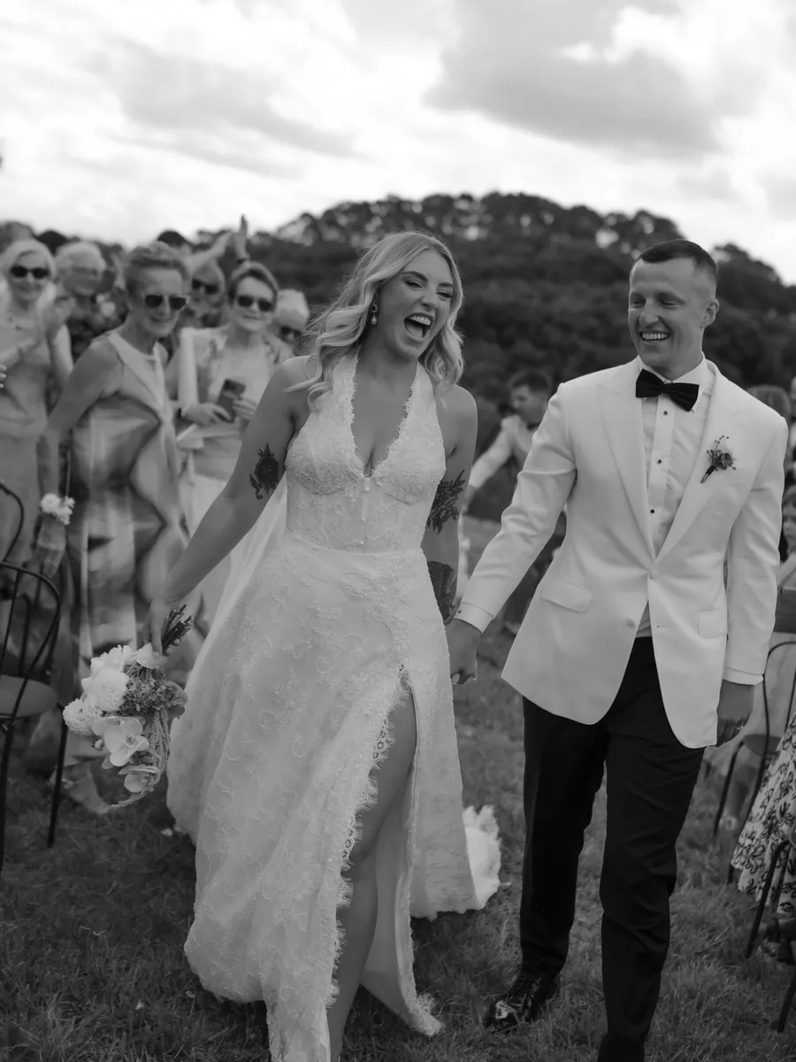Black and white image of newlyweds laughing as they walk
