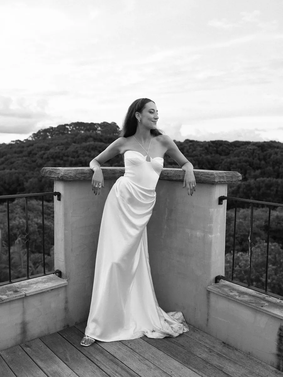 Black and white image of a bride leaning on a balcony