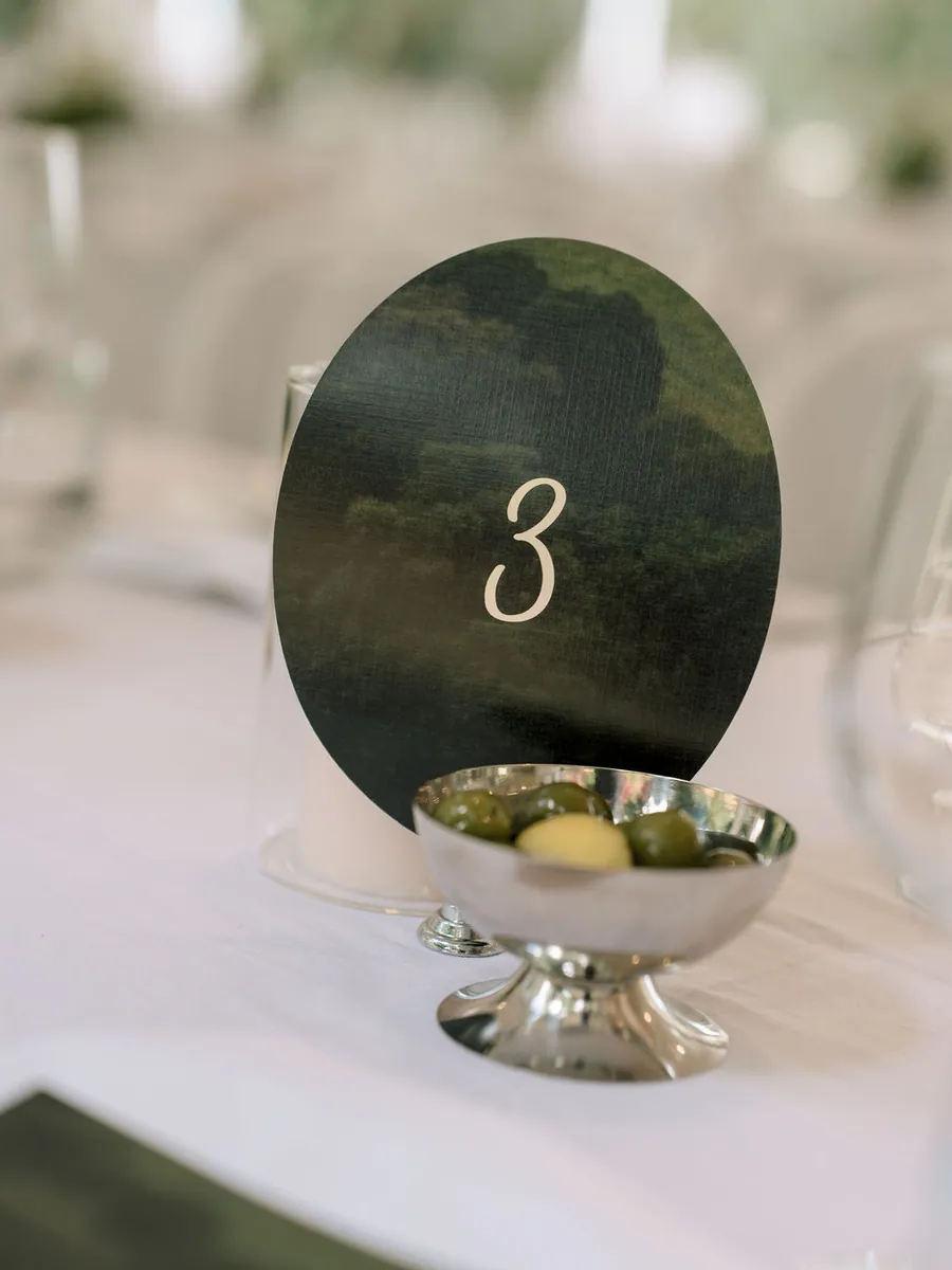 Table number card and silver bowl on a white tablecloth